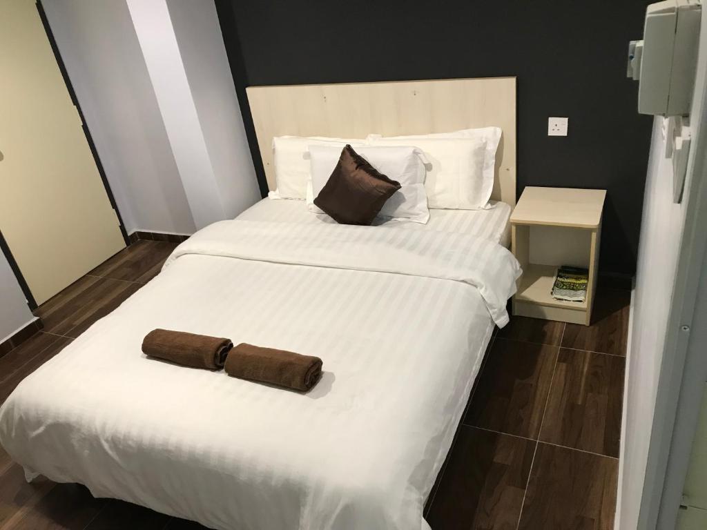 - un grand lit blanc avec 2 oreillers bruns dans l'établissement Hotel dan Restoran Seri Kangsar, à Kuala Kangsar