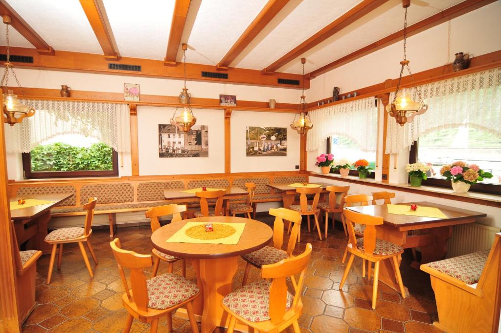un restaurante con mesas y sillas de madera y ventanas en Pension / Ferienwohnungen Scheid, en Kestert