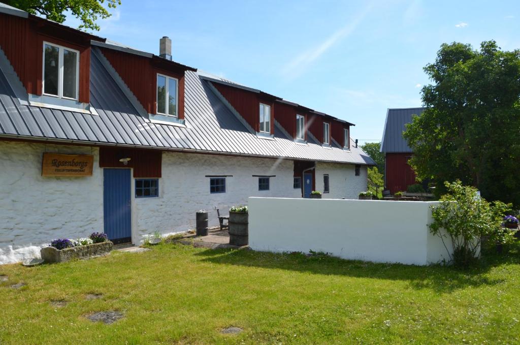 una casa blanca con una valla delante en Rosenborgs Friluftspensionat, en Färjestaden