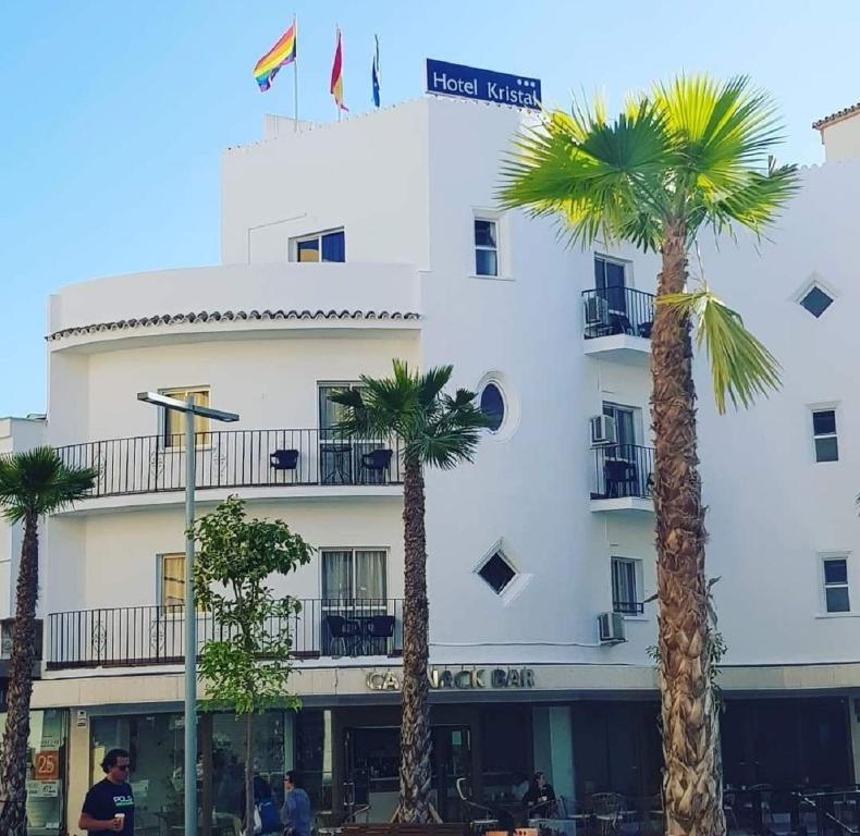 a white building with palm trees in front of it at Kristal in Torremolinos