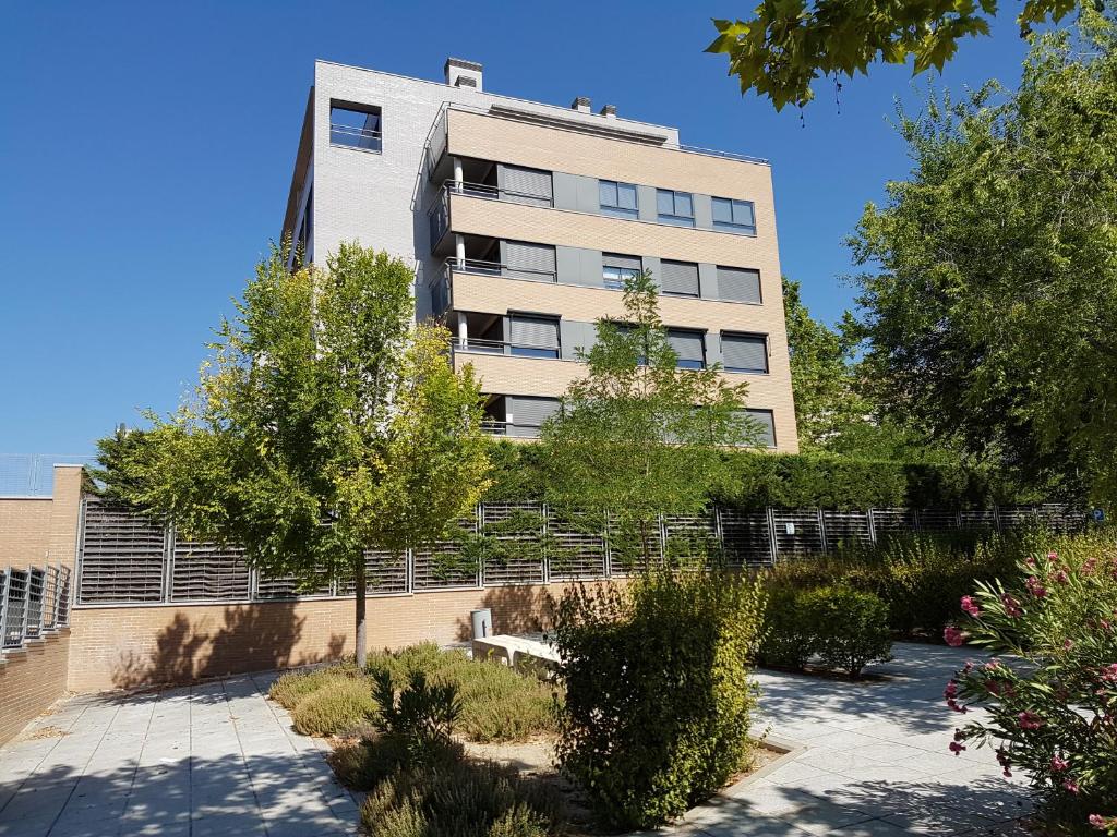 un grand bâtiment avec des arbres devant lui dans l'établissement Bonita vivienda en San Sebastian de los Reyes, à San Sebastián de los Reyes