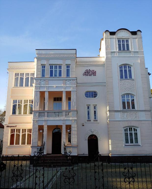 Biały budynek z płotem przed nim w obiekcie Willa Warta w mieście Krynica Morska