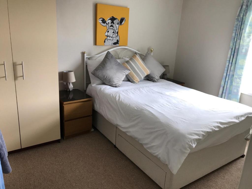 ポーツチュワートにあるPortstewart Holiday Homeのベッドルーム1室(白いベッド1台、壁に牛の絵付)