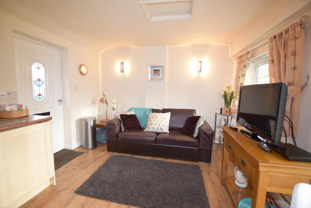 a living room with a couch and a flat screen tv at Little Rushbrook Cottages in Tanworth