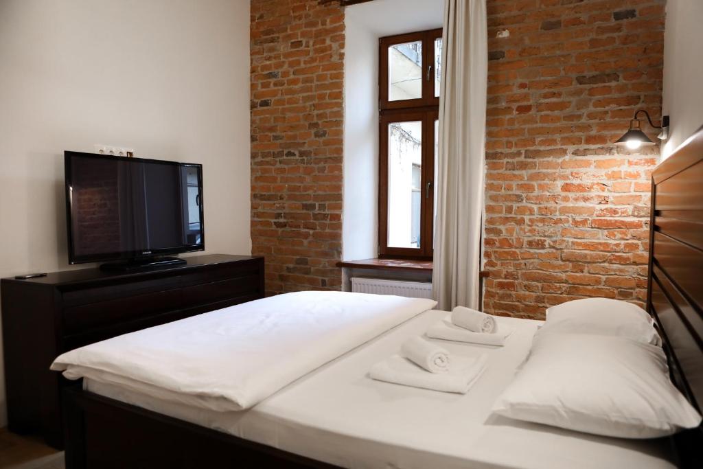 een slaapkamer met een bed, een televisie en een bakstenen muur bij Contessa Central Studio in Cluj-Napoca