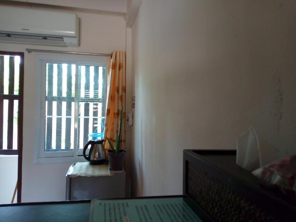 a living room with a window and a table with a keyboard at Charlee House in Trang