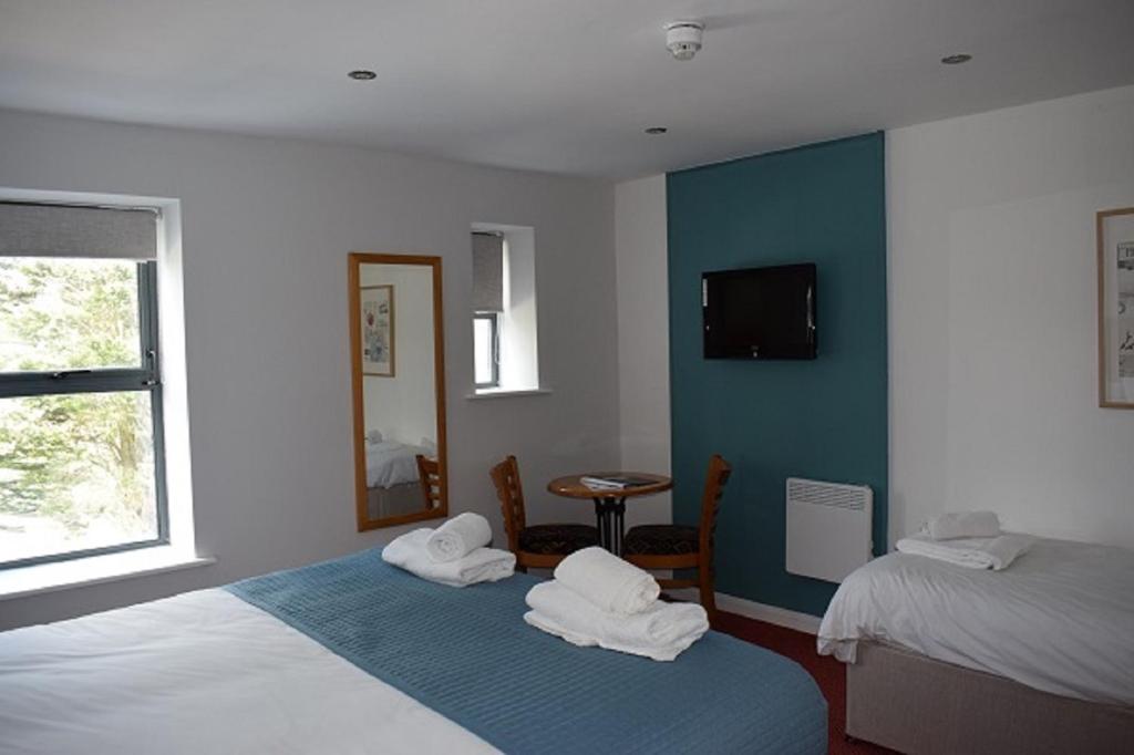 a hotel room with two beds and a television at Newlands Holidays in Bridport