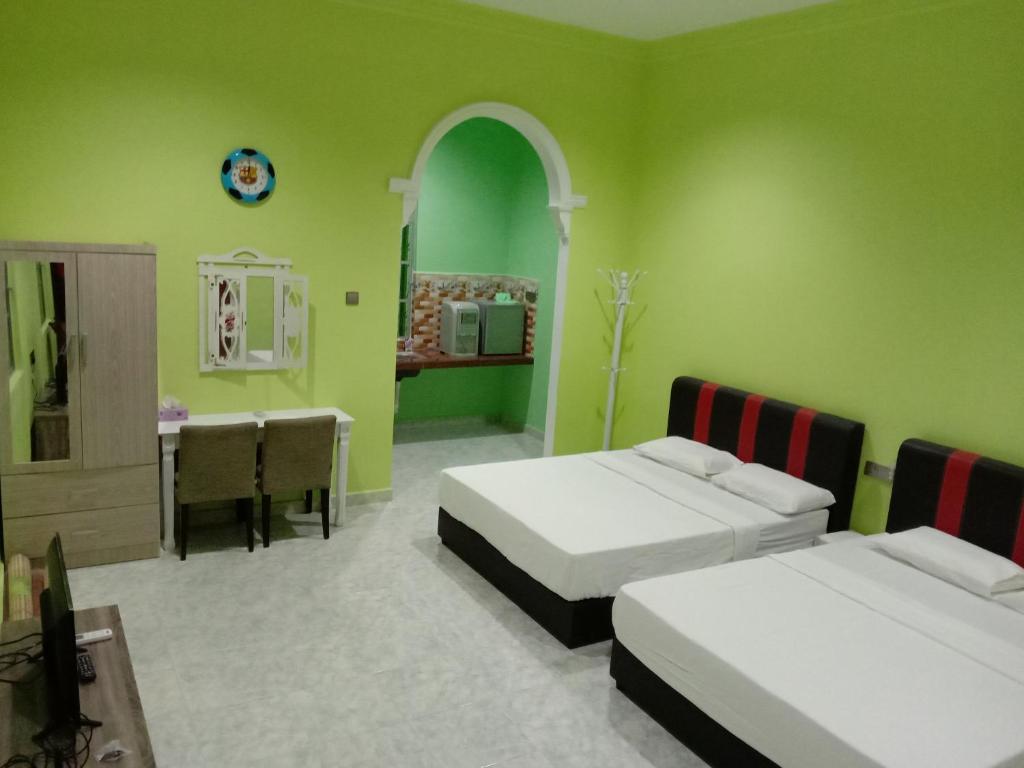 a green room with two beds and a table and a sink at DYANA INN TRANSIT ROOMS in Kota Bharu