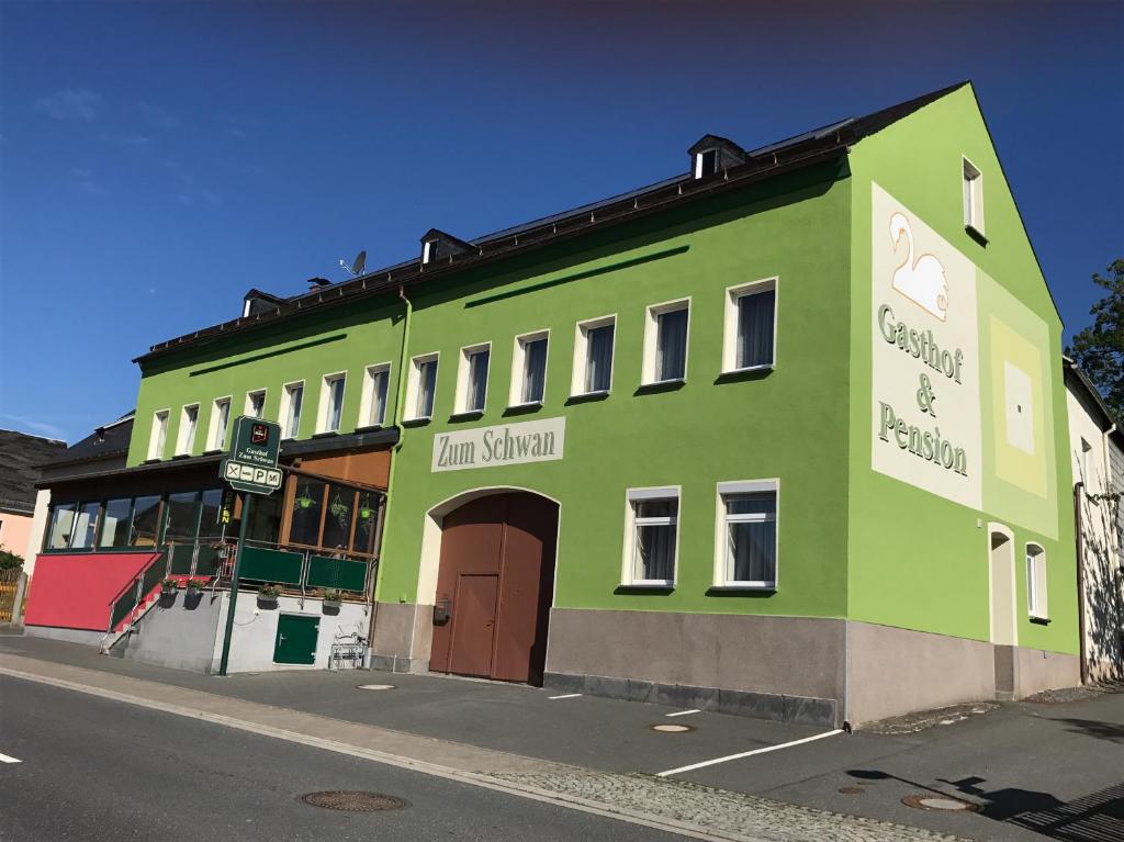 ein grünes Gebäude an der Straßenseite in der Unterkunft Gasthof „Zum Schwan“ in Langenbach