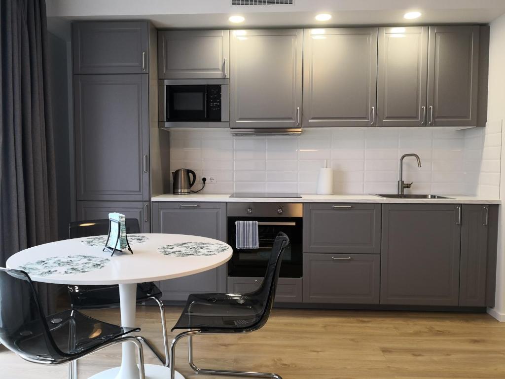 a kitchen with a white table and black appliances at Spacious apartment close to the Old Town in Vilnius