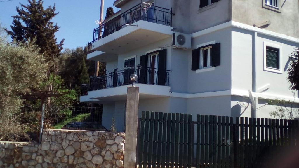 a white house with a fence in front of it at Monika Lefkada in Tsoukaladhes