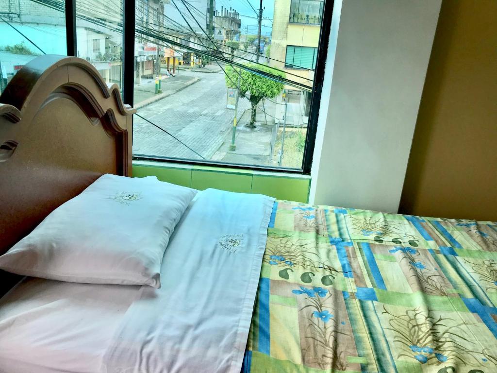 1 dormitorio con 1 cama y vistas a la calle en Kanoas Hostal, en Puyo
