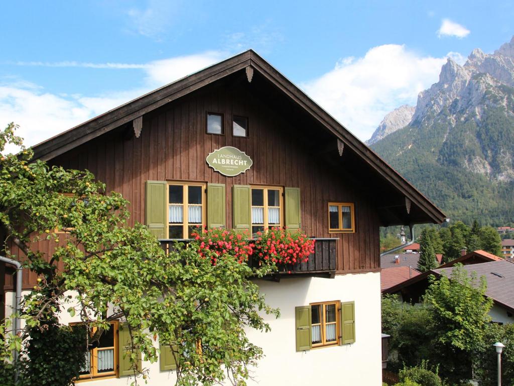 abweichendes Gebäude mit Balkon mit Blumen darauf in der Unterkunft Landhaus Albrecht in Mittenwald