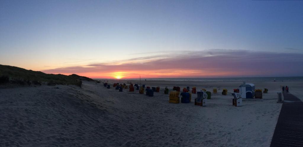 eine Gruppe von Menschen am Strand bei Sonnenuntergang in der Unterkunft Hotel-Pension Peterhof in Juist