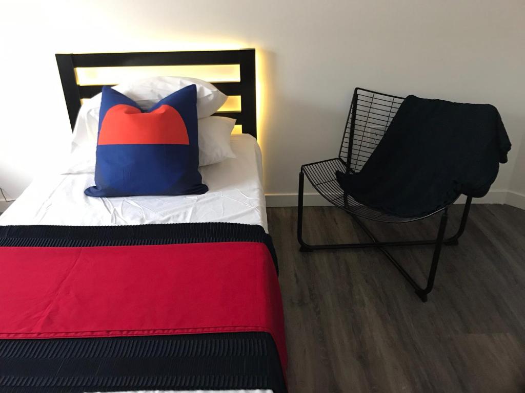 a bed with a pillow and a chair in a room at Modern GuestHouse Ironbound Newark with KITCHEN-FastTrainToNYC-OneStopToAirport in Newark