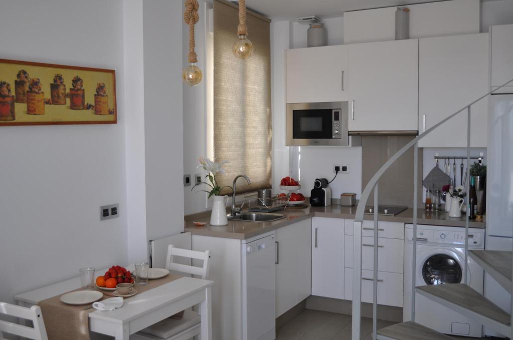 a kitchen with white cabinets and a sink and a dishwasher at Apartamentos en Paseo Maritimo in El Rompido