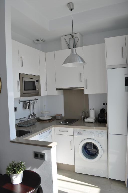 a white kitchen with a washing machine and a microwave at Apartamentos en Paseo Maritimo in El Rompido