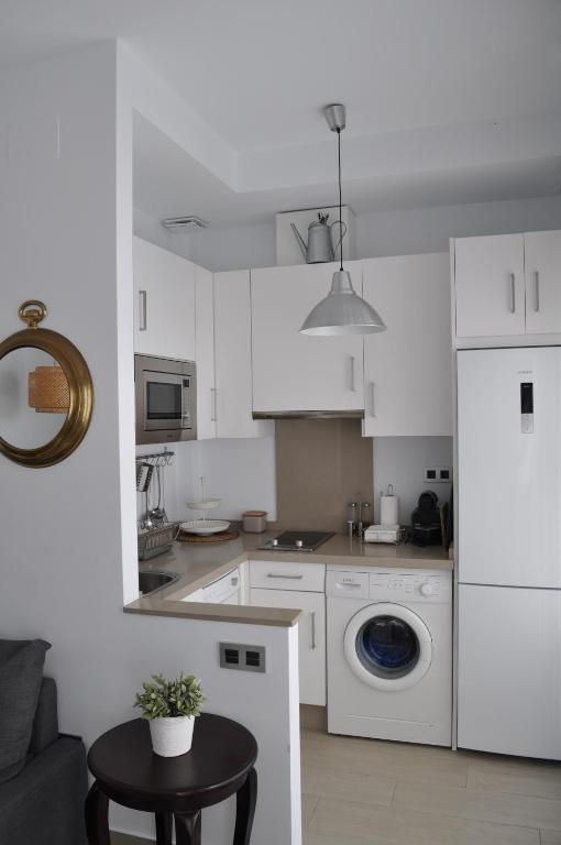 a white kitchen with a washing machine and a table at Apartamentos en Paseo Maritimo in El Rompido
