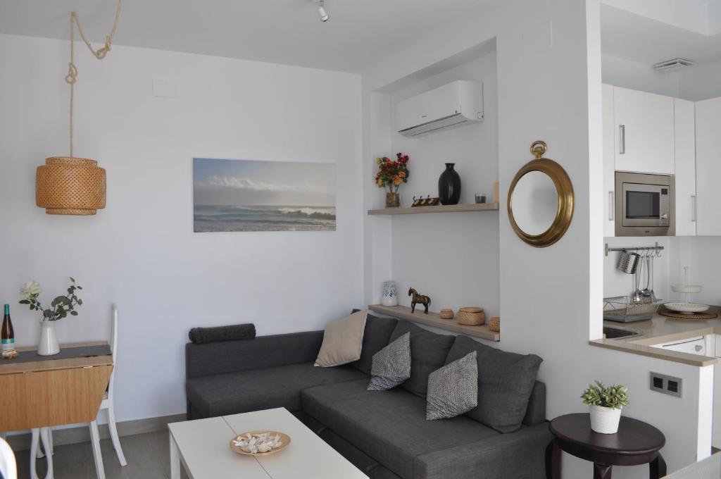 a living room with a gray couch and a kitchen at Apartamentos en Paseo Maritimo in El Rompido