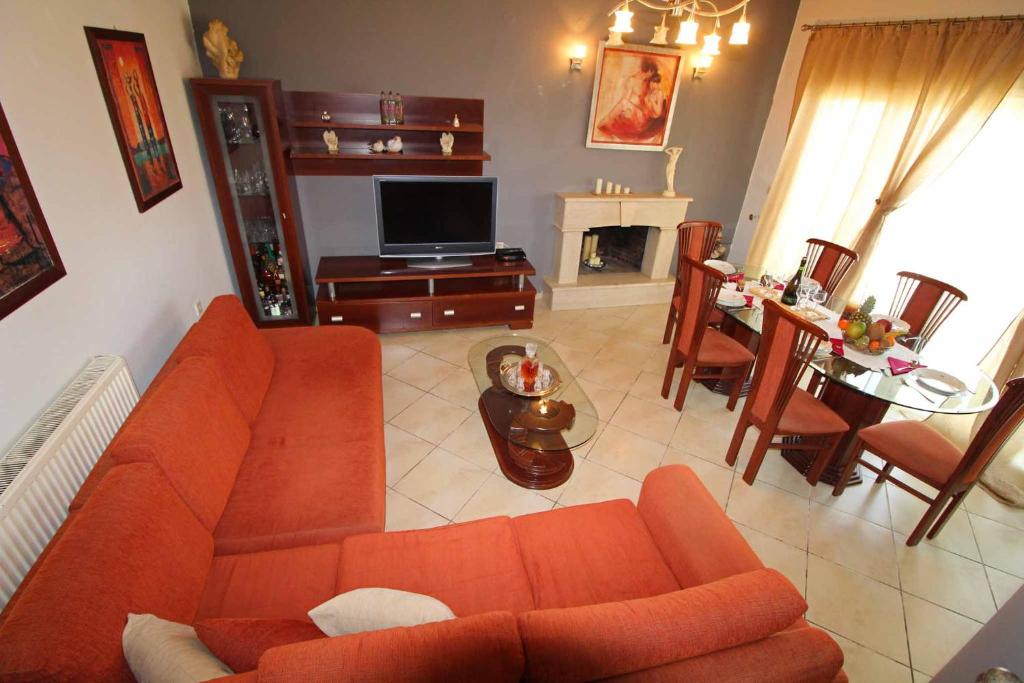 salon z pomarańczową kanapą i stołem w obiekcie Natasa’s home Agios Ioannis Karousades w Korfu