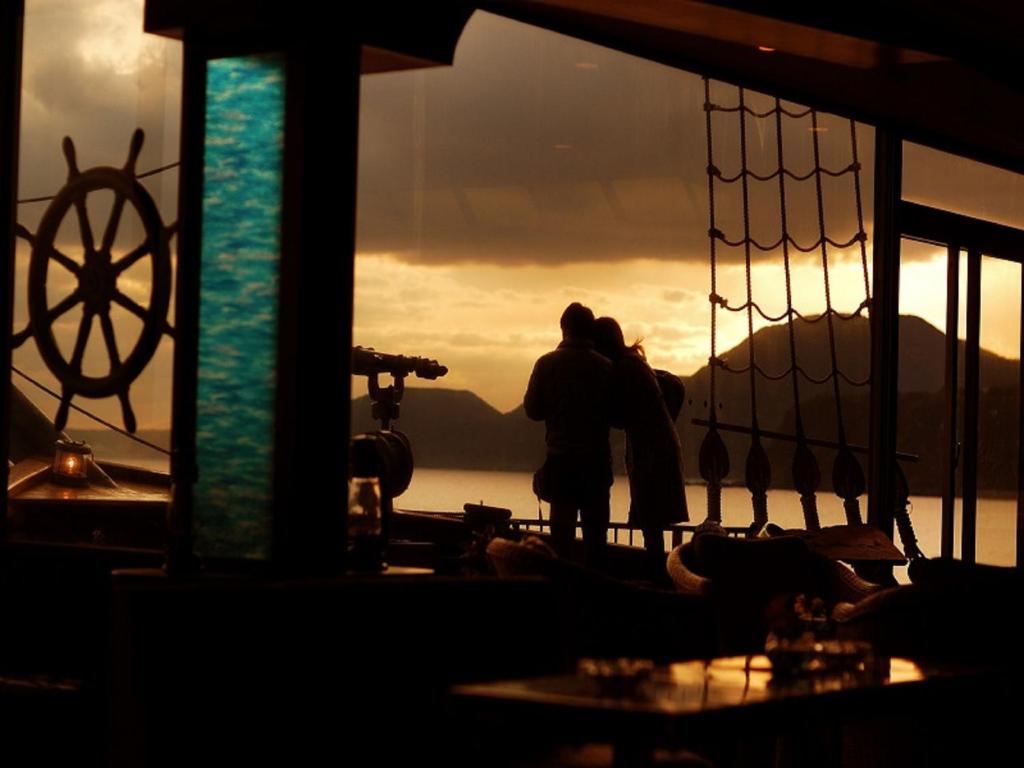 a couple standing on a balcony looking at the sunset at Inatori Tokai Hotel Yuen in Higashiizu