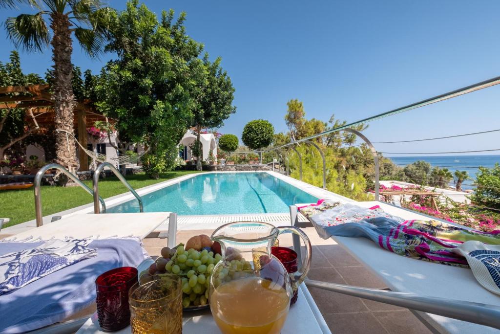 uma mesa com uma tigela de fruta ao lado de uma piscina em Santorini Mystique Garden Villa em Kamari