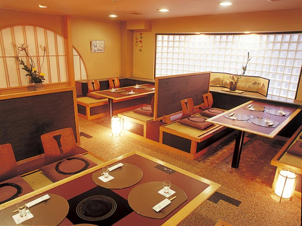 a large room with tables and chairs and a tv at Inatori Tokai Hotel Yuen in Higashiizu