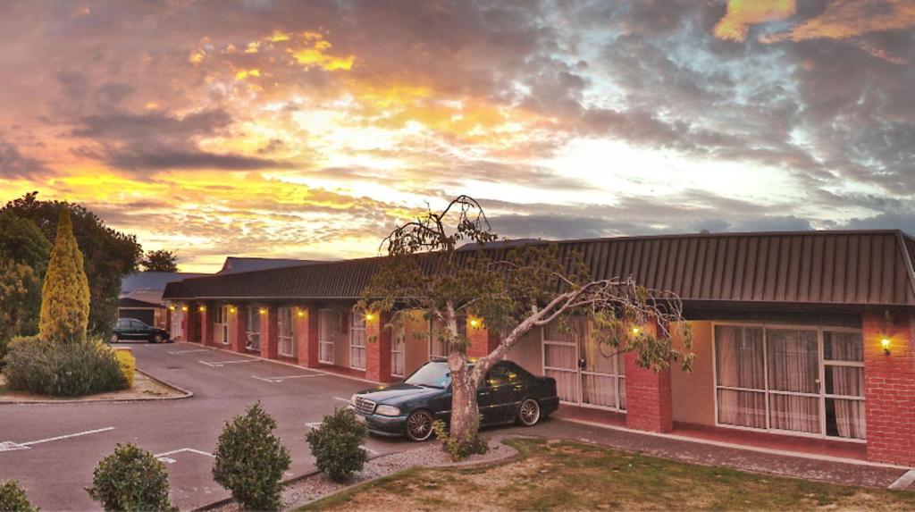 un bâtiment avec une voiture garée sur un parking dans l'établissement Palmerston North Motel, à Palmerston North