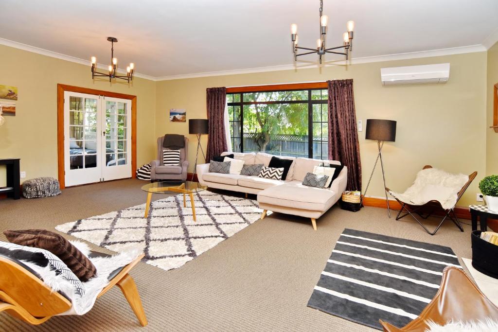 een woonkamer met een bank en een stoel bij Racecourse Villa - Christchurch Holiday Home in Christchurch