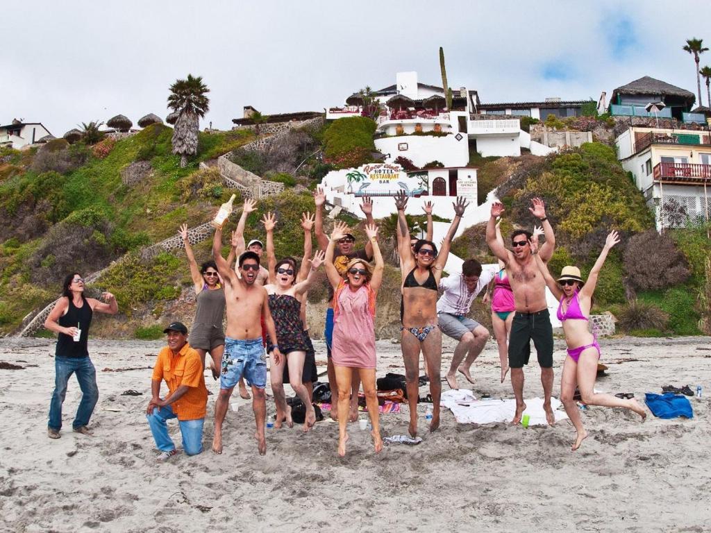 a group of people jumping on the beach at Poco Cielo Hotel in Rosarito