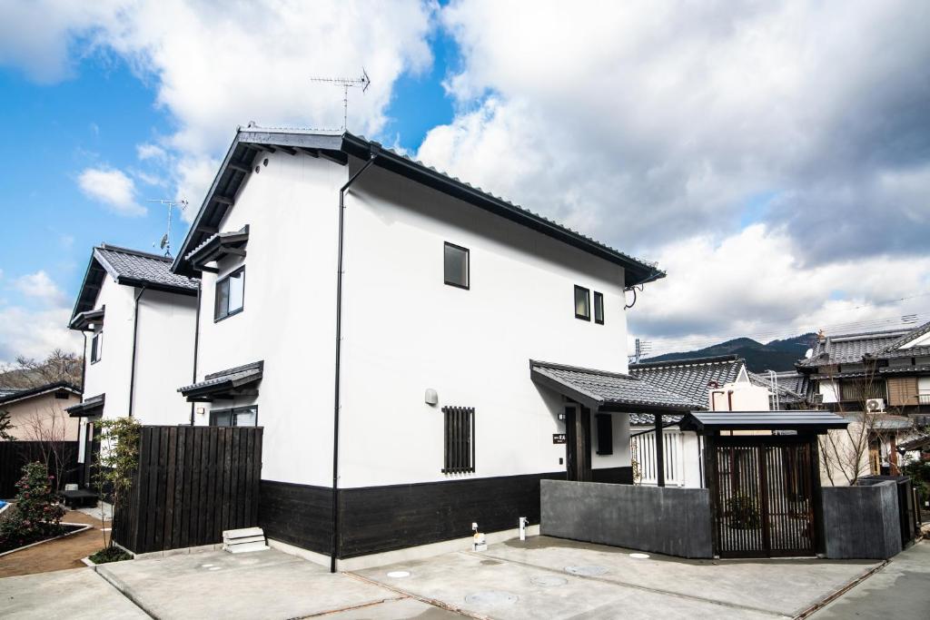 una casa blanca con techo negro en Yufuin Matsuri-an Nagomiya, en Yufu