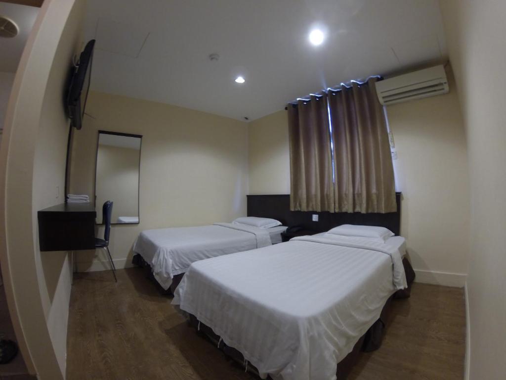Hotel Kinabalu في كوتا كينابالو: غرفة فندقية بسريرين ومرآة