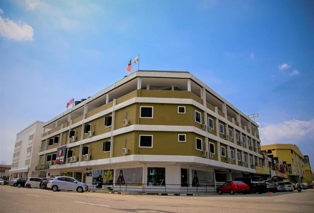 ein gelbes Gebäude mit Autos auf einem Parkplatz in der Unterkunft Apple Suites Hotel in Sitiawan