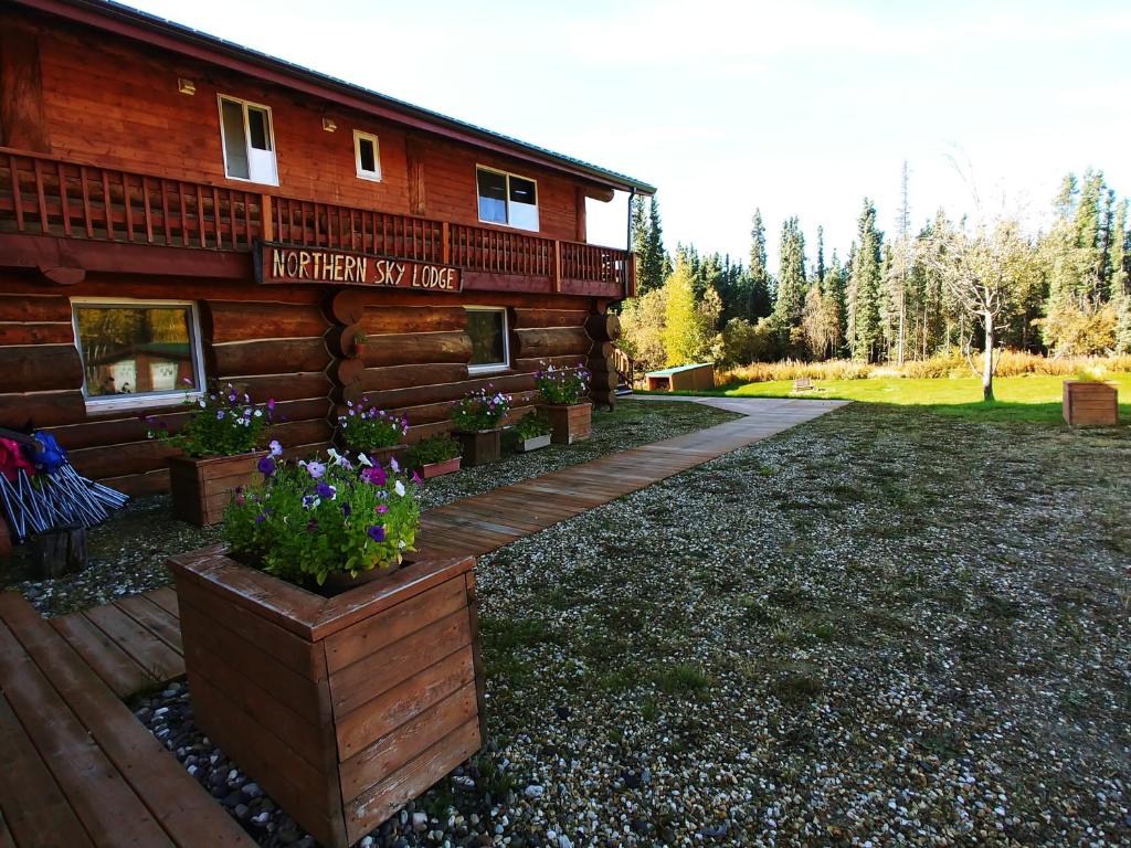 a log cabin with flowers in front of it at Northern Sky Lodge in Fairbanks