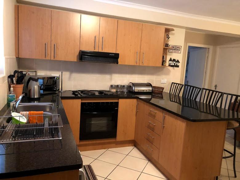 a kitchen with wooden cabinets and a black counter top at Innikol 26 in Mossel Bay