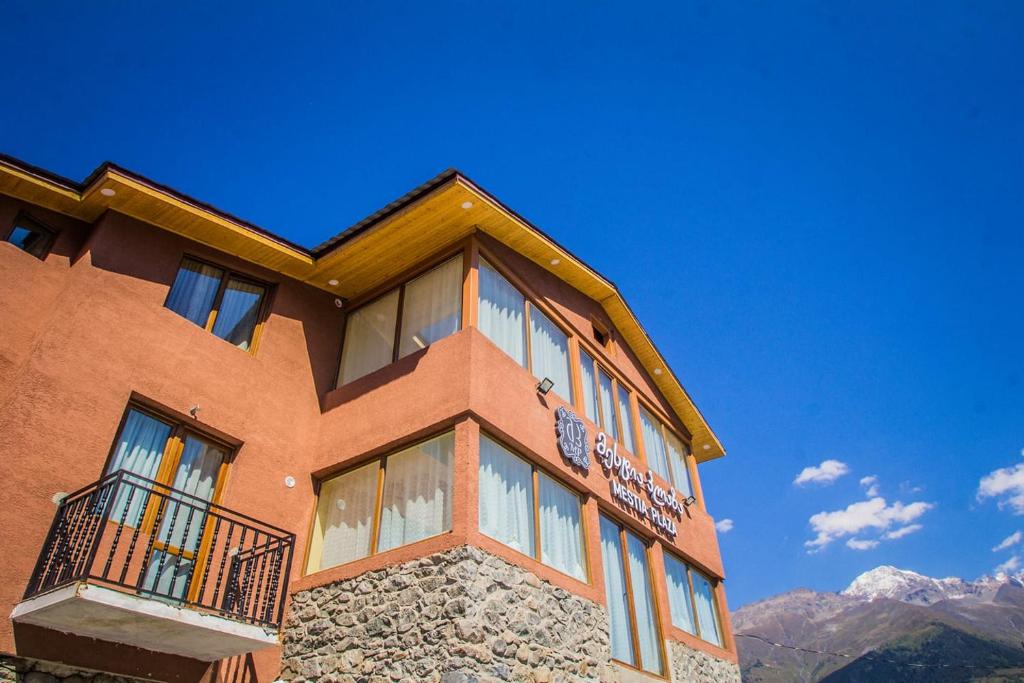 un edificio con ventanas y montañas al fondo en Mestia Plaza en Mestia