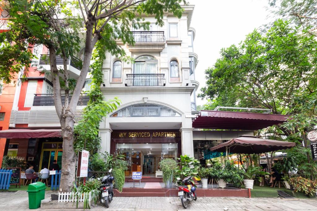 a white building with a tree in front of it at Sunny Hotel and Apartment in Ho Chi Minh City