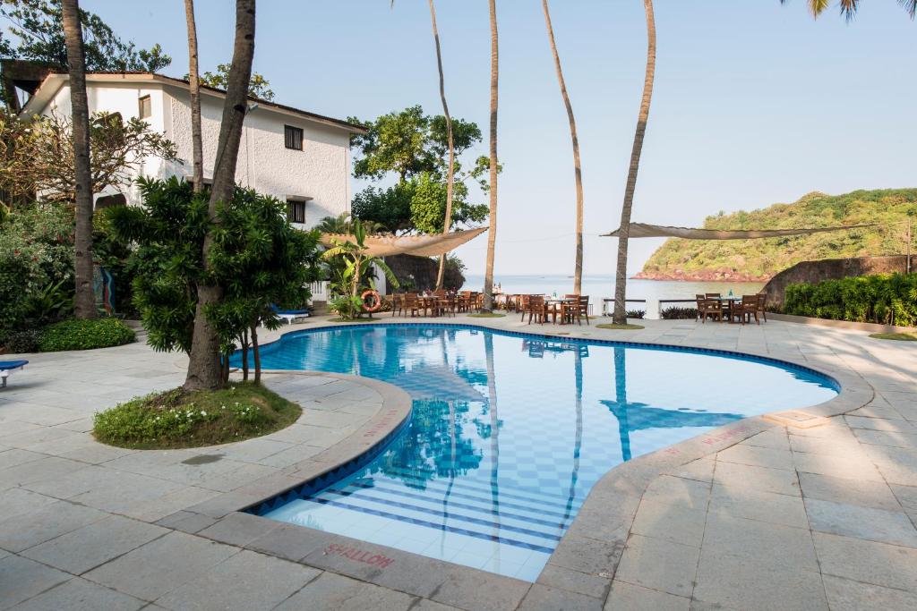 una piscina con tavoli e sedie accanto all'acqua di O Pescador an Indy Resort a Panaji