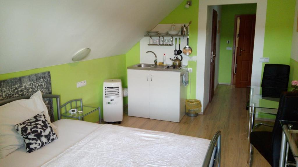 a bedroom with a bed and a kitchen with green walls at Apartments U Kašny in Kadaň