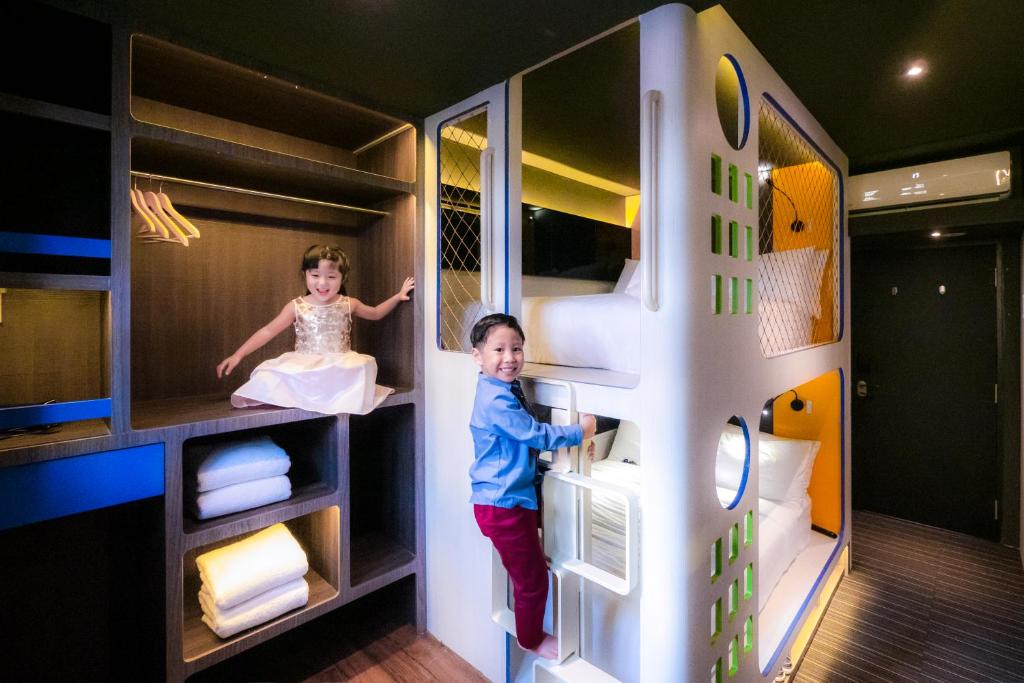 two children are playing inside of a bunk bed at CUBE Family Boutique Capsule Hotel at Chinatown in Singapore