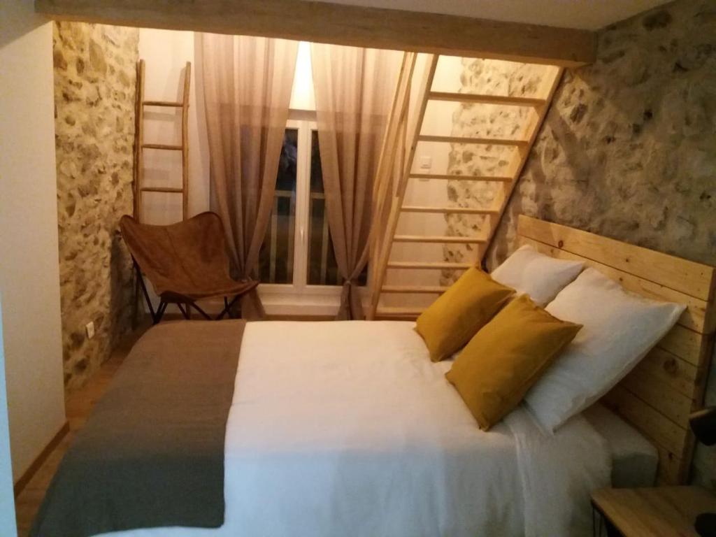 een slaapkamer met een bed, een stoel en een raam bij la feda gîte Pyrénées Ariégeoises in Auzat