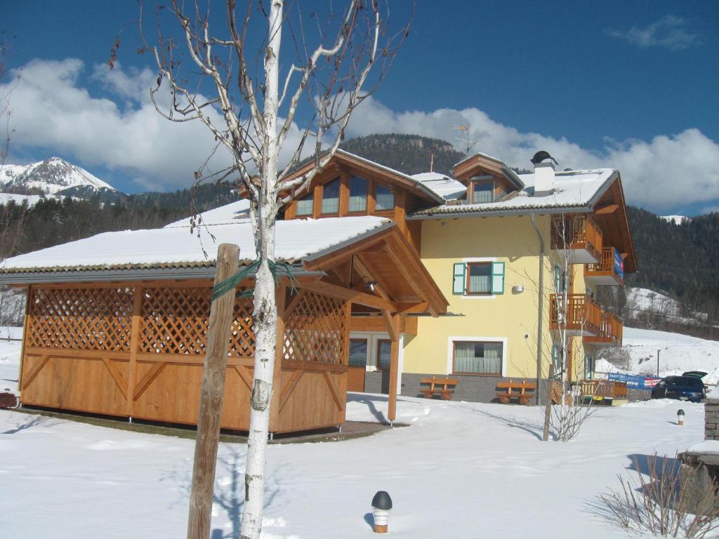 una casa en invierno con nieve en el suelo en Agritur Maso Chemela, en Cavalese