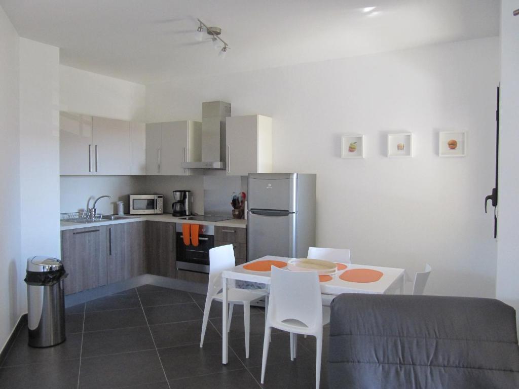 T2 de standing idéalement situé في بروبريانو: مطبخ مع طاولة وكراسي بيضاء في الغرفة