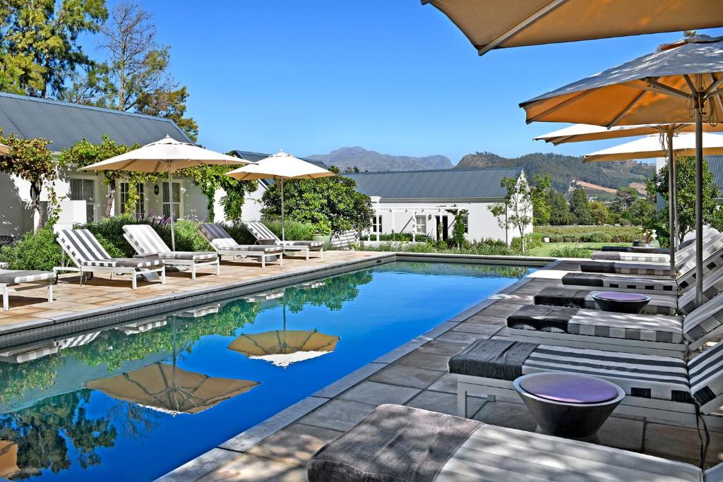 フランシュホークにあるLavender Farm Boutique Guest Houseの家の隣にある椅子とパラソルのあるプール