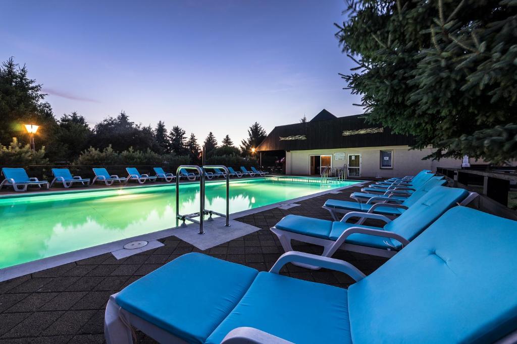 a group of blue lounge chairs next to a swimming pool at Lech Resort & Spa in Łeba