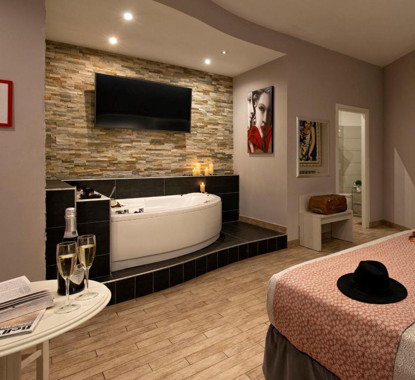 uma casa de banho com banheira e uma televisão numa parede de tijolos em Five Rooms Rome Guesthouse em Roma