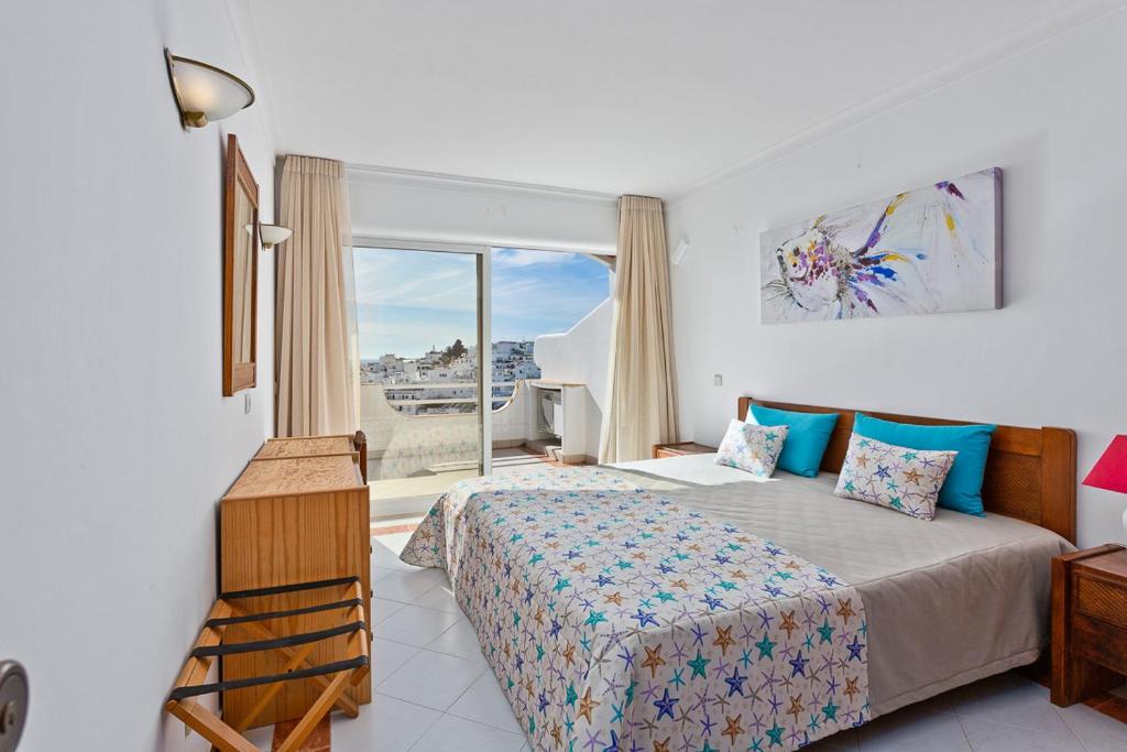 een slaapkamer met een bed en een groot raam bij AZUL/MAR ALBUFEIRA 602 in Albufeira
