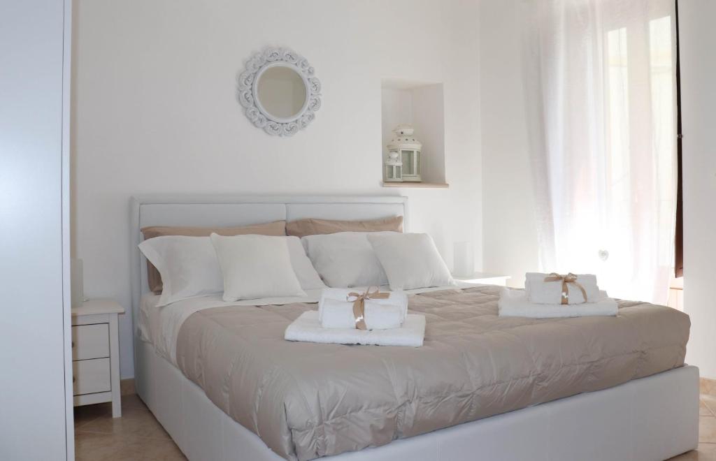 una camera bianca con un grande letto con due asciugamani bianchi di La Dolce Dimora a Fasano