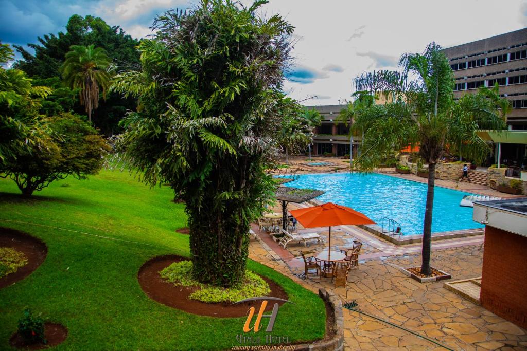a pool with a palm tree and an umbrella at Utalii Hotel in Nairobi