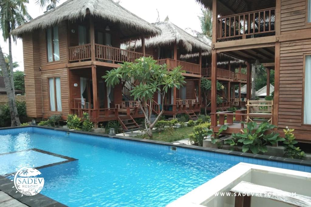 a resort with a swimming pool in front of a building at Sadev Resort in Gili Trawangan